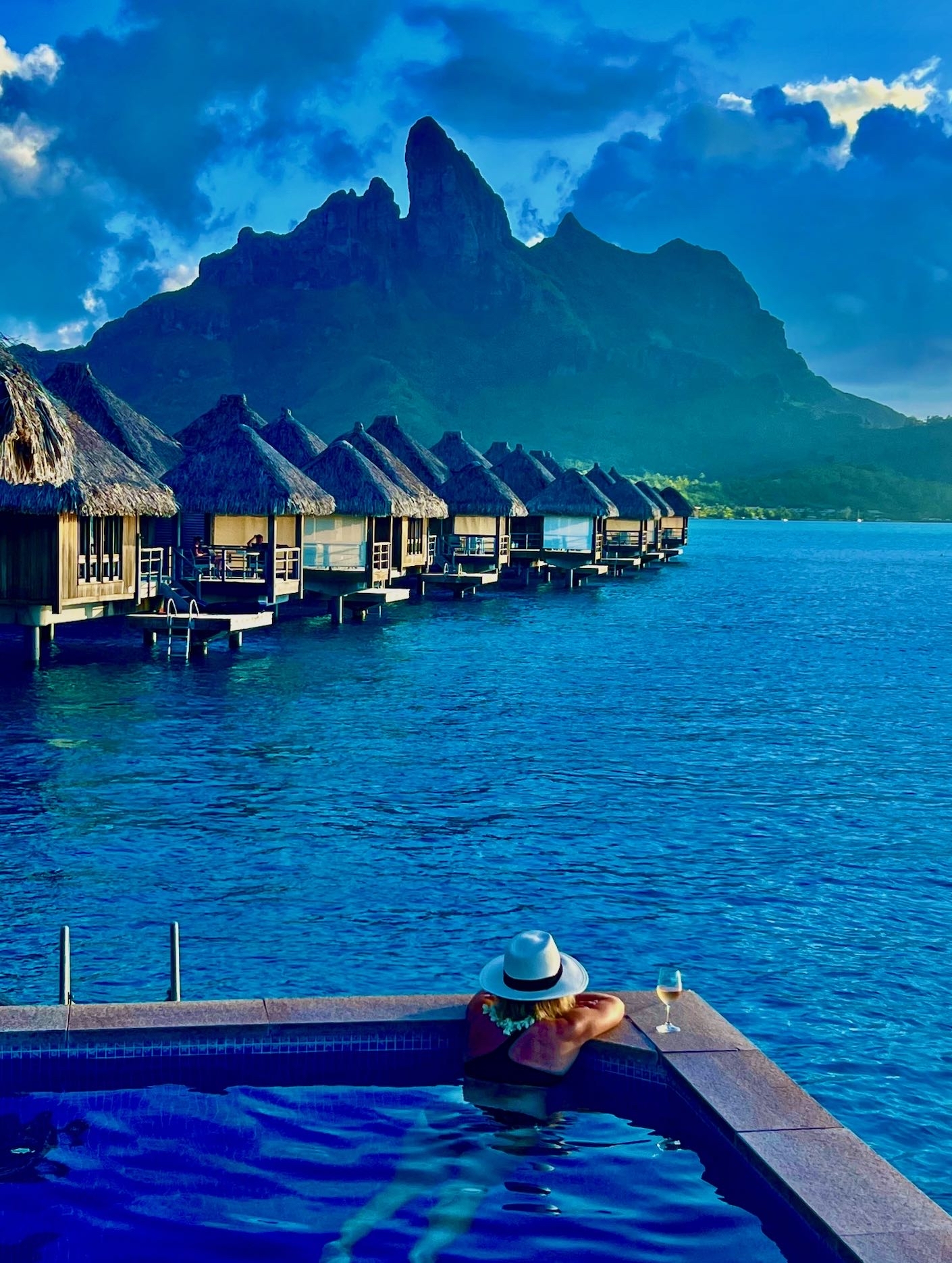 Overwater bungalows and the peaks of Bora Bora seen from an infinity pool